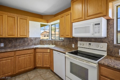 Kitchen featuring white appliances, a sink, decora