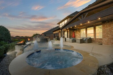 The raised spa has trickling falls leading to the lagoon style pool with bubbler fountains, tanning shelf, and umbrella stands. Note the cathedral height covered patio, fire bowls, and landscape lighting!