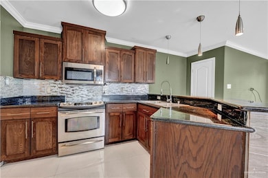 Kitchen with a peninsula, crown molding, stainless steel appliances, and a sink