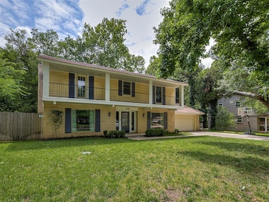 View of front of home with a balcony, concrete driveway, a garage, and brick siding