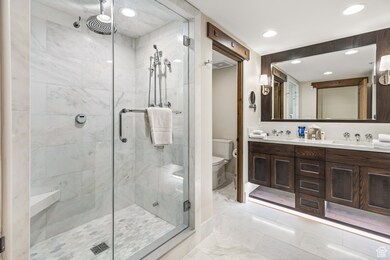 Full bathroom featuring a marble finish shower, double vanity, light marble finish floors, and recessed lighting