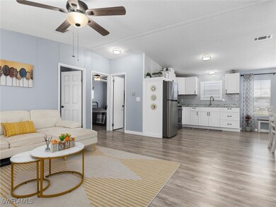 Living room with ceiling fan, sink, wood-type floo