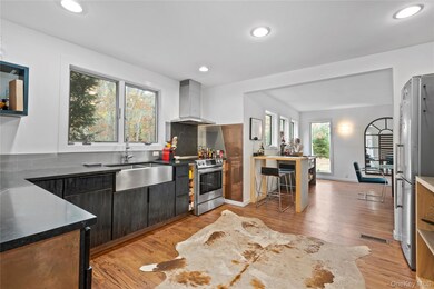 Kitchen featuring light wood-type flooring, ventilation hood, appliances with stainless steel finishes, tasteful backsplash, and recessed lighting