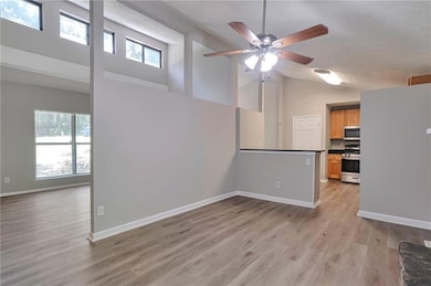 Spare room featuring high vaulted ceiling, a ceiling fan, and light wood-type flooring