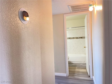 Corridor with wood finished floors and a textured
