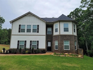 View of front of home featuring board and batten siding, a front yard, and brick siding