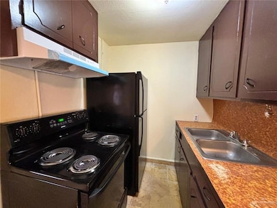 Kitchen featuring black range with electric cooktop, decorative backsplash, dark brown cabinets, and sink