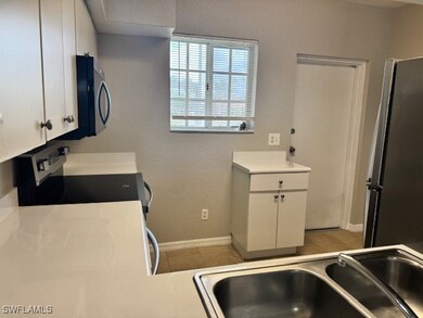 Kitchen with a sink, black microwave, range, white
