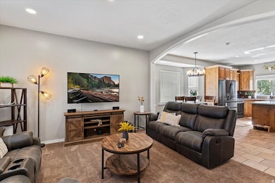 Living room with a chandelier, arched walkways, light carpet, and recessed lighting