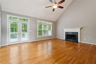Unfurnished living room featuring a premium fireplace, ceiling fan, light wood-type flooring, high vaulted ceiling, and french doors