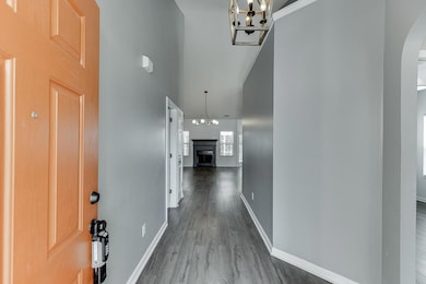 Entryway featuring a chandelier, arched walkways, dark wood finished floors, a fireplace, and a towering ceiling