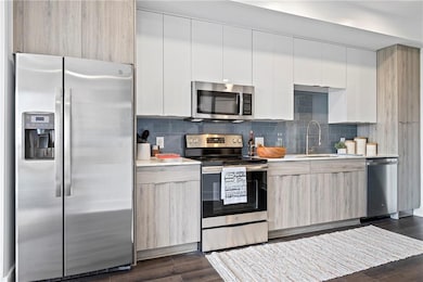Kitchen featuring white cabinets, sink, appliances