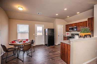 Kitchen featuring black appliances, light countertops, lofted ceiling, dark wood-style floors, and baseboards