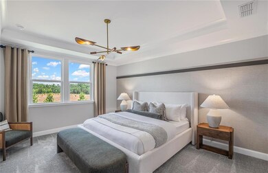 Carpeted bedroom with a raised ceiling, baseboards, and a chandelier