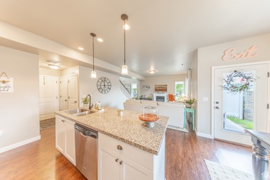 Kitchen with white cabinets, light stone counters, dishwasher, dark wood-style floors, and recessed lighting