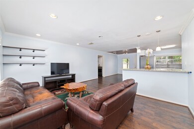 Modern open layout connecting the living and kitchen for easy gatherings. Pendant lighting accents breakfast bar between living area and spacious open kitchen.
