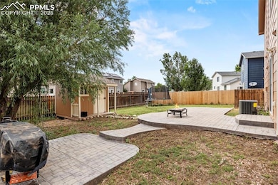 Fenced backyard featuring a shed, a trampoline, a patio area, a fire pit, and a residential view