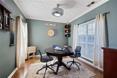 Office space with a textured ceiling, crown molding, and wood finished floors
