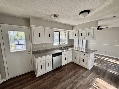 Kitchen with dishwasher, white cabinets, dark wood
