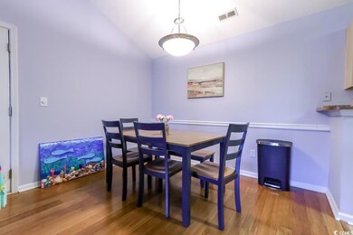 Dining area featuring wood finished floors, vaulted ceiling, and baseboards