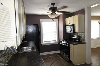 Kitchen featuring tasteful backsplash, black appliances, dark hardwood / wood-style flooring, sink, and ceiling fan
