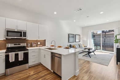 Kitchen featuring appliances with stainless steel finishes, a peninsula, recessed lighting, white cabinets, and backsplash