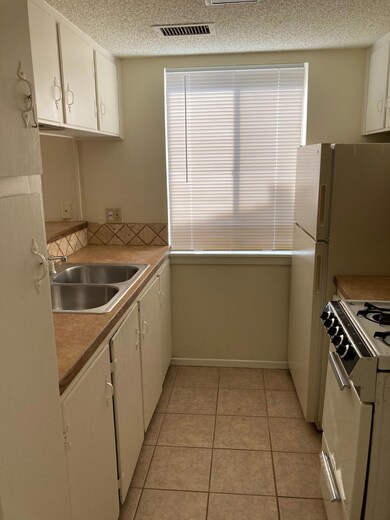 Kitchen with stove, white cabinets, light tile pa