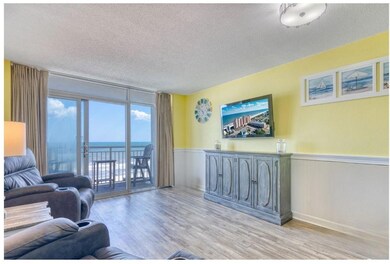 Living area featuring a textured ceiling, wainscoting, light wood-style flooring, and a water view