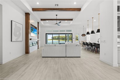 Living room featuring a ceiling fan, beamed ceiling, a tray ceiling, light wood finished floors, and recessed lighting