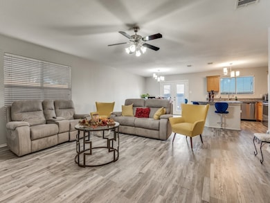 Living area with a chandelier, a ceiling fan, light wood-type flooring, and french doors
