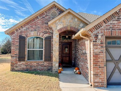 Entrance to property with brick siding, a lawn, and stone siding