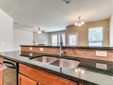 Kitchen featuring a sink, plenty of natural light, brown cabinetry, and a ceiling fan