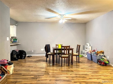 Dining room with wood finished floors, a textured ceiling, and a ceiling fan
