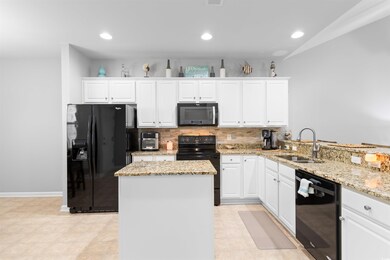 Kitchen with white cabinetry, black appliances, an