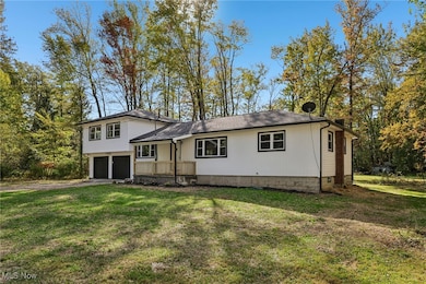 Tri-level home with a front lawn, an attached garage, driveway, and roof with shingles