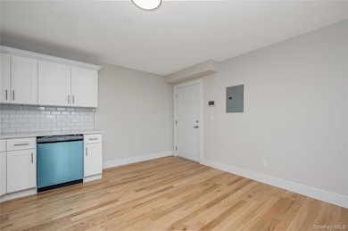 Kitchen with white cabinets, backsplash, dishwashing machine, and light wood-type flooring