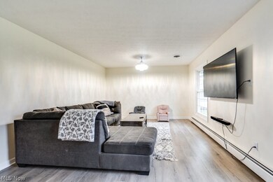 Living room with light hardwood / wood-style floors and a baseboard heating unit