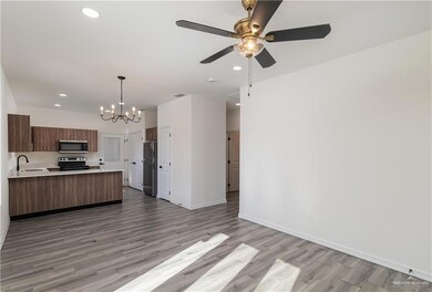 Kitchen with a sink, open floor plan, light countertops, light wood-style flooring, and appliances with stainless steel finishes