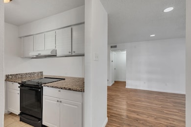 Kitchen with electric range, white cabinetry, a te