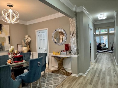Hallway with crown molding, light wood-style flooring, and a chandelier