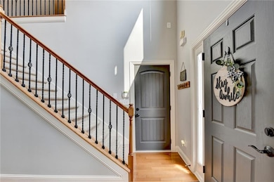 Entryway featuring wood finished floors, stairway, and a towering ceiling
