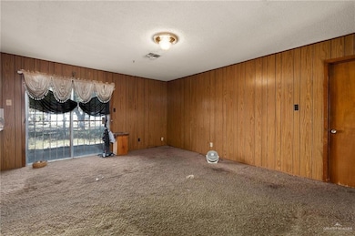 Carpeted empty room with wood walls and a textured ceiling