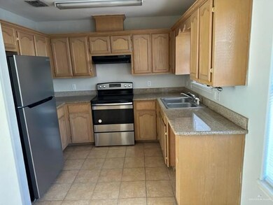 Kitchen with appliances with stainless steel finishes, a sink, ventilation hood, and light tile patterned flooring