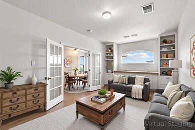 Living room featuring french doors, wood finished floors, and built in shelves - virtually staged