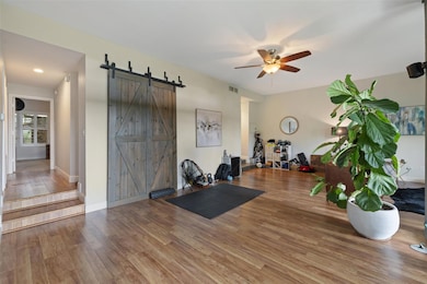 Exercise room featuring a ceiling fan, a barn doo