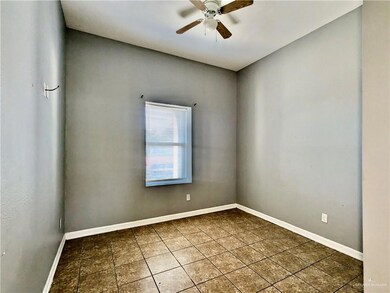 Empty room featuring tile patterned floors, ceiling fan, and baseboards