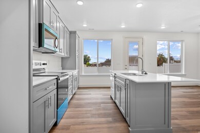 Kitchen featuring gray cabinets, stainless steel appliances, an island with sink, light wood-type flooring, and recessed lighting