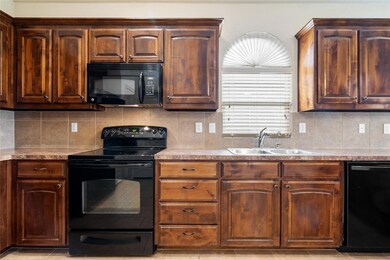 Kitchen with black appliances, sink, and tasteful backsplash
