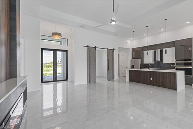 Kitchen featuring a barn door, stainless steel appliances, a center island with sink, decorative light fixtures, and ceiling fan