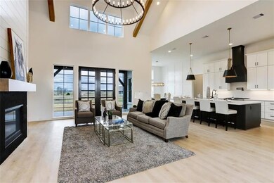 Living room with visible vents, light wood-style floors, a large fireplace, and a chandelier